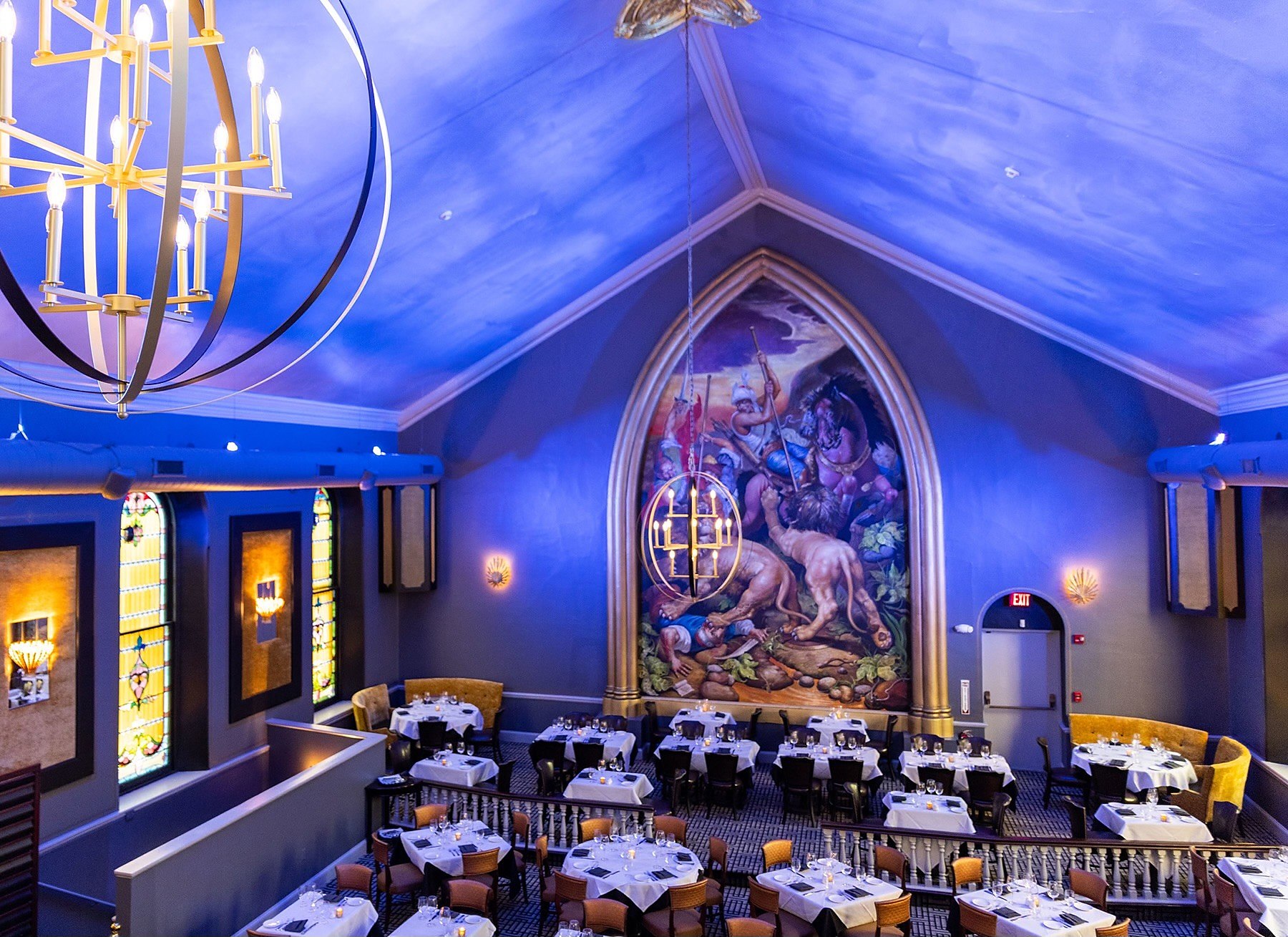 The main dining room at OldeStone, set for dinner beneath the mural